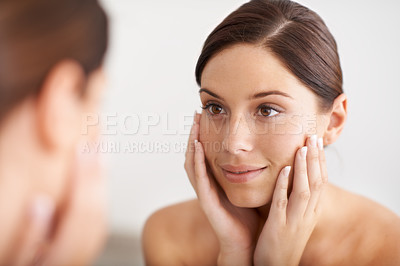 Buy stock photo A gorgeous young woman looking at her reflection in the mirror with her hands on her face