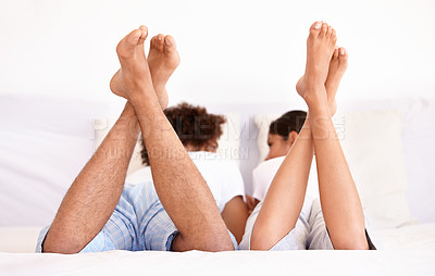 Buy stock photo Rearview shot of a young couple lying on the bed having a discussion