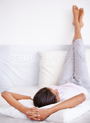 Buy stock photo Rearview shot of a young woman sleep with her legs propped up on a pillow