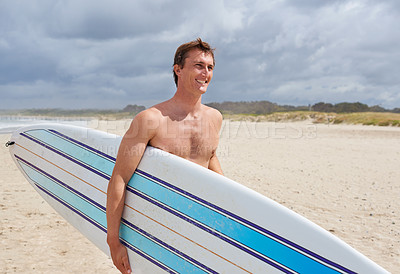 Buy stock photo A young man holding his surfboard at the beach