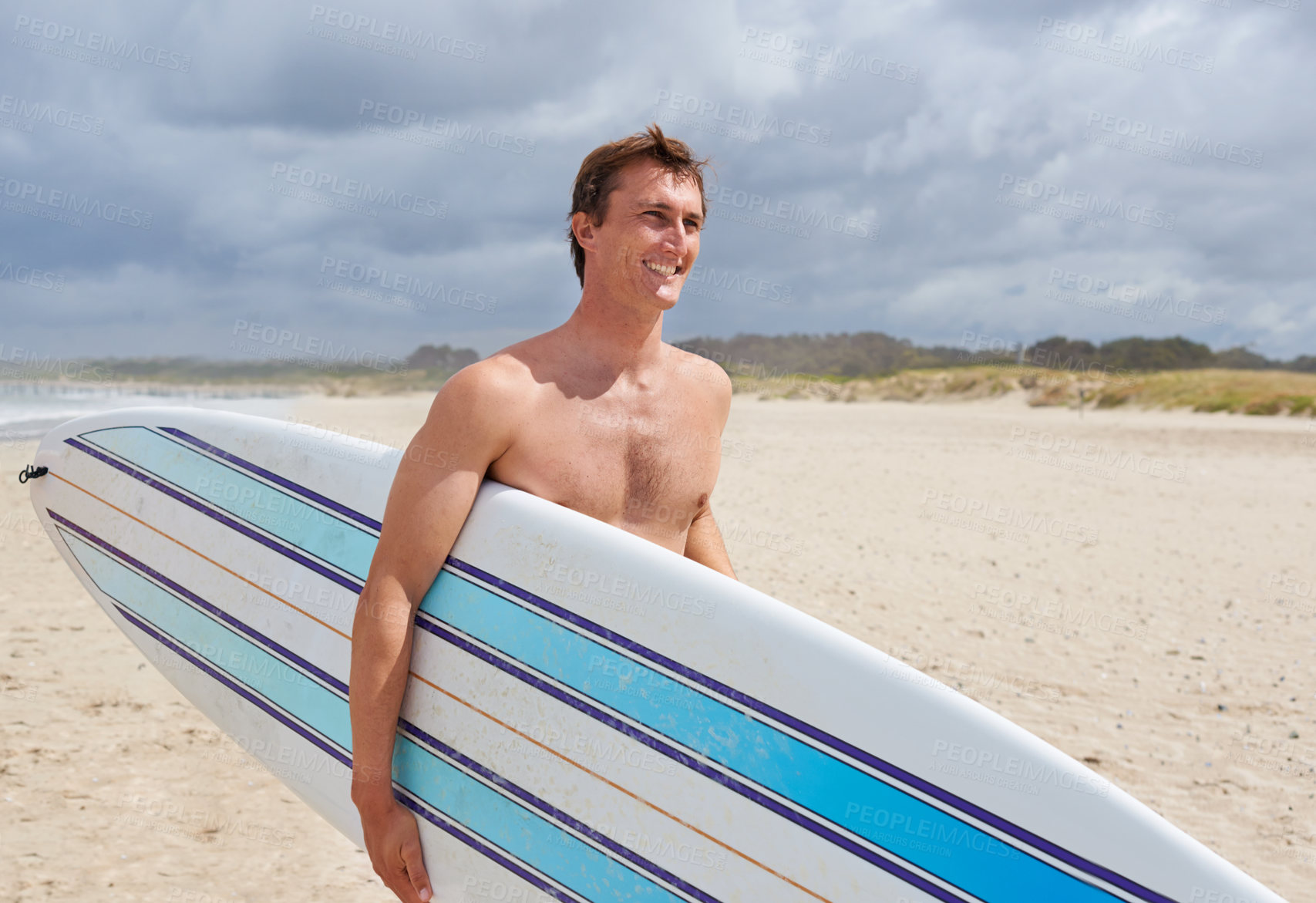 Buy stock photo A young man holding his surfboard at the beach