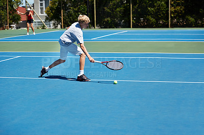 Buy stock photo Shot of a young boy playing tennis on a sunny day