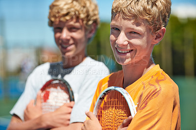 Buy stock photo Two friends standing together and holding their tennis rackets on the court