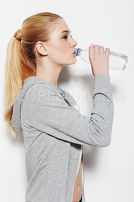 Buy stock photo Studio shot of a young woman in exercise clothing drinking from a water bottle