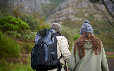 Buy stock photo Outdoor, hiking and couple in mountain, holding hands and walking with backpack, nature and bonding together. Forest, adventure and trekking in path, field and exercise for fitness and travel
