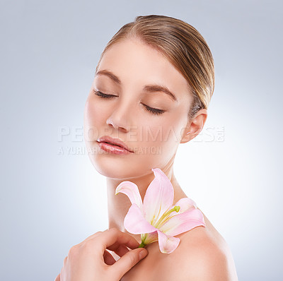 Buy stock photo Studio shot of a young a model holding a flower to her bare shoulder