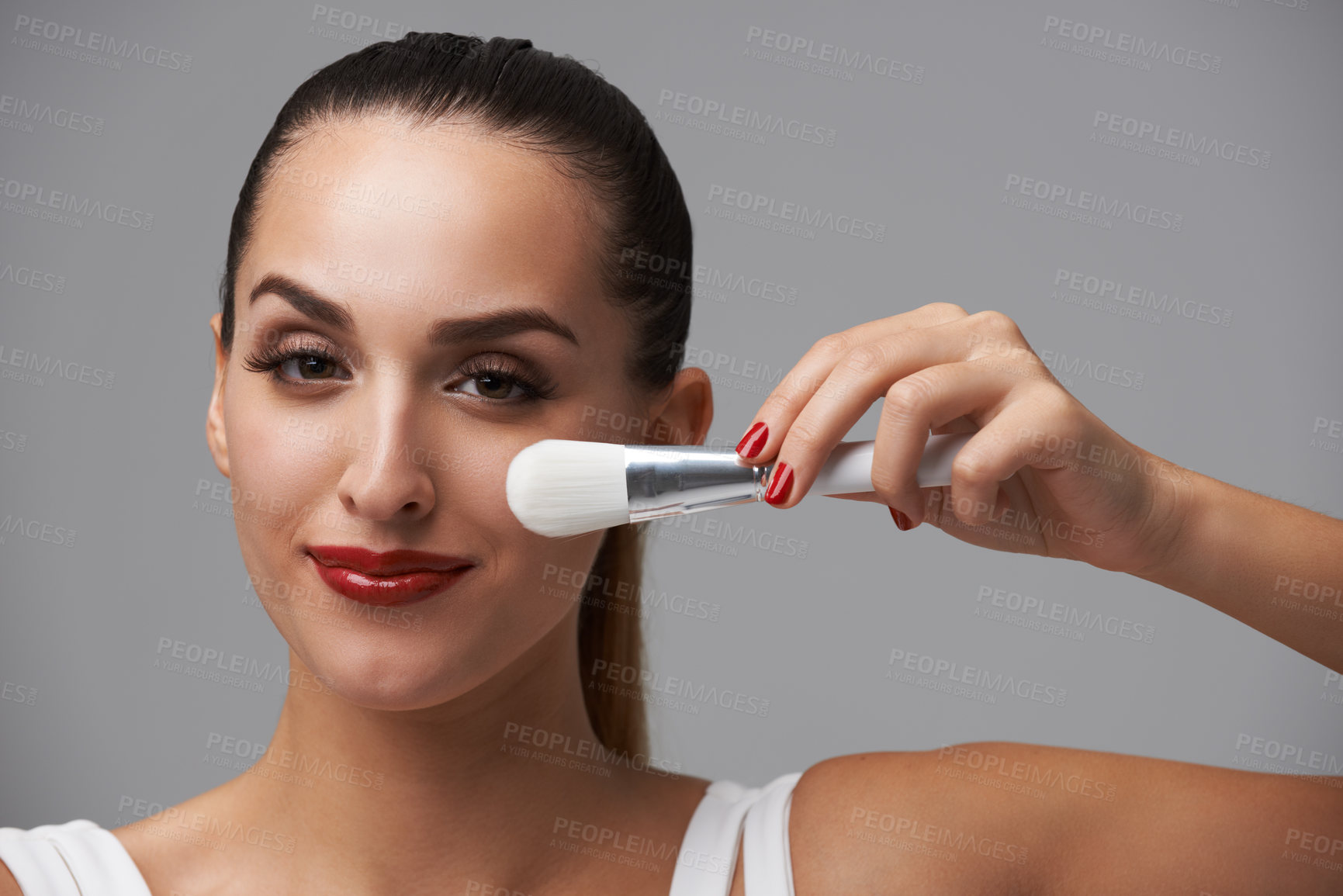 Buy stock photo Woman, face and brush for makeup, beauty and red lipstick with manicure and cosmetic tools on grey background. Portrait, equipment with color nails and lips, foundation or powder with smile in studio