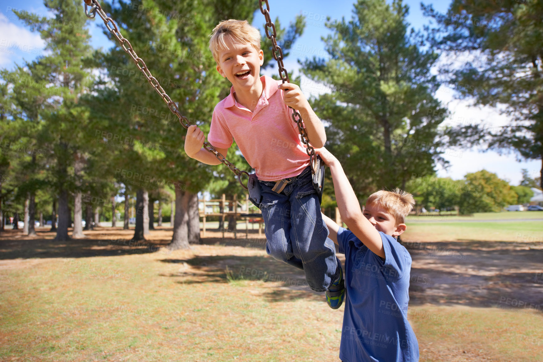 Buy stock photo A young boy enjoying the swings on the playground with friend