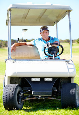 Buy stock photo A mature man driving a golf cart across the course