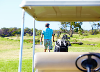 Buy stock photo Rear-view of a golfer walking away with a golf cart in the foreground
