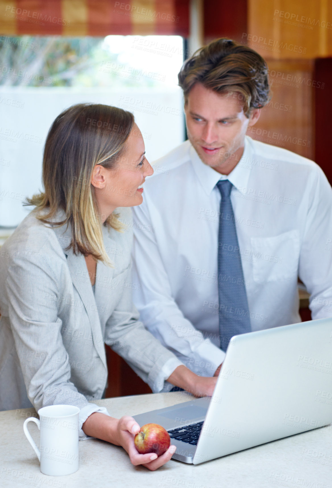 Buy stock photo Happy business couple, laptop and discussion with apple for breakfast, healthy meal or morning nutrition in kitchen at home. Man or woman talking in remote work with computer, coffee or organic fruit