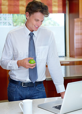 Buy stock photo Happy man, coffee and apple by laptop in kitchen for morning, healthy breakfast or diet at home. Male person or freelancer with cup of tea or organic fruit by computer for business, meal or nutrition
