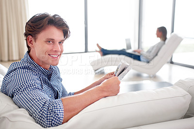 Buy stock photo Man, newspaper and portrait on sofa with relax for story, article or information with smile in living room. Person, news or morning routine on couch with print media or knowledge for break in lounge 