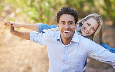 Buy stock photo A loving young couple standing together outdoors with their arms outstretched