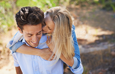 Buy stock photo Happy couple, kiss and cheek in piggyback for love, bonding or support for outdoor affection in nature. Face of young woman and man smile for embrace, hug or romantic back ride in forest together