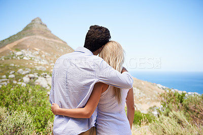 Buy stock photo Rear view of a young couple embracing as they enjoy a view of the mountainside