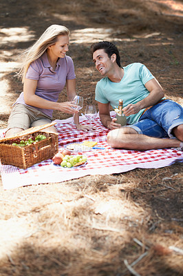 Buy stock photo Couple, picnic and champagne in forest with love, romantic celebration and summer date on valentines day. Young people with food, fruits and bottle with wine glasses in woods or nature on anniversary