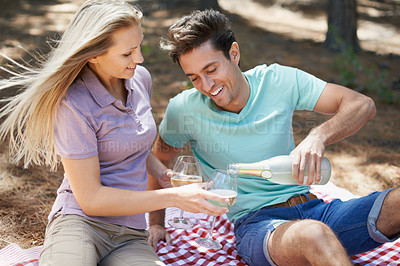 Buy stock photo Happy couple, wine glass and picnic in nature or park for celebration of love, holiday and valentines day. Young people on a date with champagne bottle, drinks and excited for anniversary in a forest