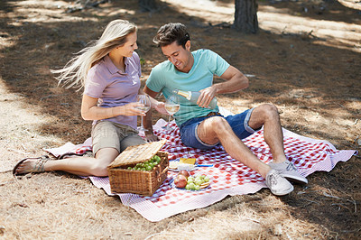 Buy stock photo Couple, wine glass and picnic outdoor in nature or park for celebration of love, holiday date and valentines day. Young people with fruits basket, drinks or champagne bottle in forest on anniversary