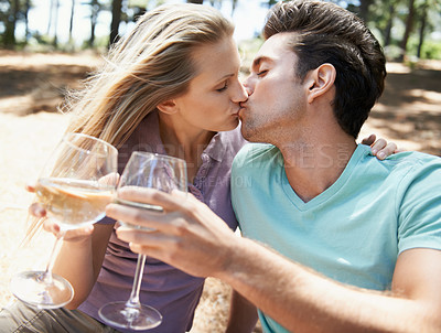 Buy stock photo Couple, kiss and wine glass in nature or forest for celebration of love, holiday and valentines day. Man and woman together with alcohol, drinks and toast on outdoor date for anniversary in woods