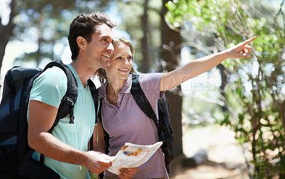 Buy stock photo Couple, hiking in nature and map for direction, documents guide or location information of forest travel or journey. Man and woman trekking with infographics, search woods and pointing to destination