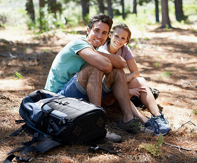 Buy stock photo Couple, hiking break and portrait in forest for outdoor travel, adventure and wellness journey in nature. Happy man and woman relax on ground with backpack for trekking destination, health or fitness