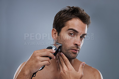 Buy stock photo A young man shaving with an electric razor