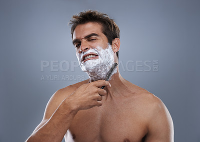 Buy stock photo Man, shaving and pain in studio portrait with grooming, skincare and wellness with stress by grey background. Person, model and anxiety with beard, facial hair removal and product for cosmetic change