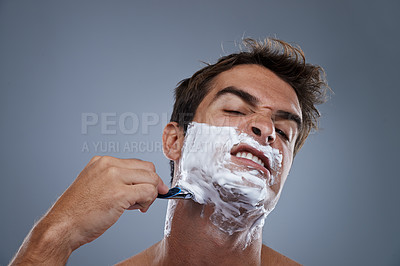 Buy stock photo Man, shaving and stress with razor in studio portrait for wellness, skin and grooming by grey background. Person, model and frustrated with beard, facial hair removal and product for cosmetic change