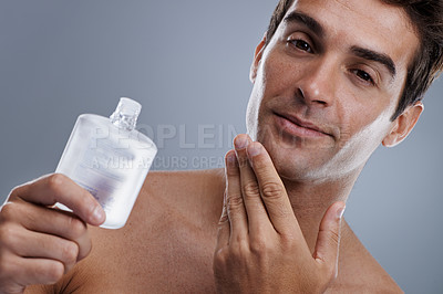 Buy stock photo Studio, portrait and man with cologne for skincare, grooming and facial treatment or aftershave. Model, face and happy with bottle for cosmetics product, fragrance and male beauty by gray background