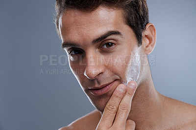 Buy stock photo Portrait, cream and man with skincare, glow and moisture on a grey studio background. Face, person and model with grooming routine and treatment with lotion and dermatology with wellness or shine