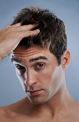 Buy stock photo A young man applying product to his hair