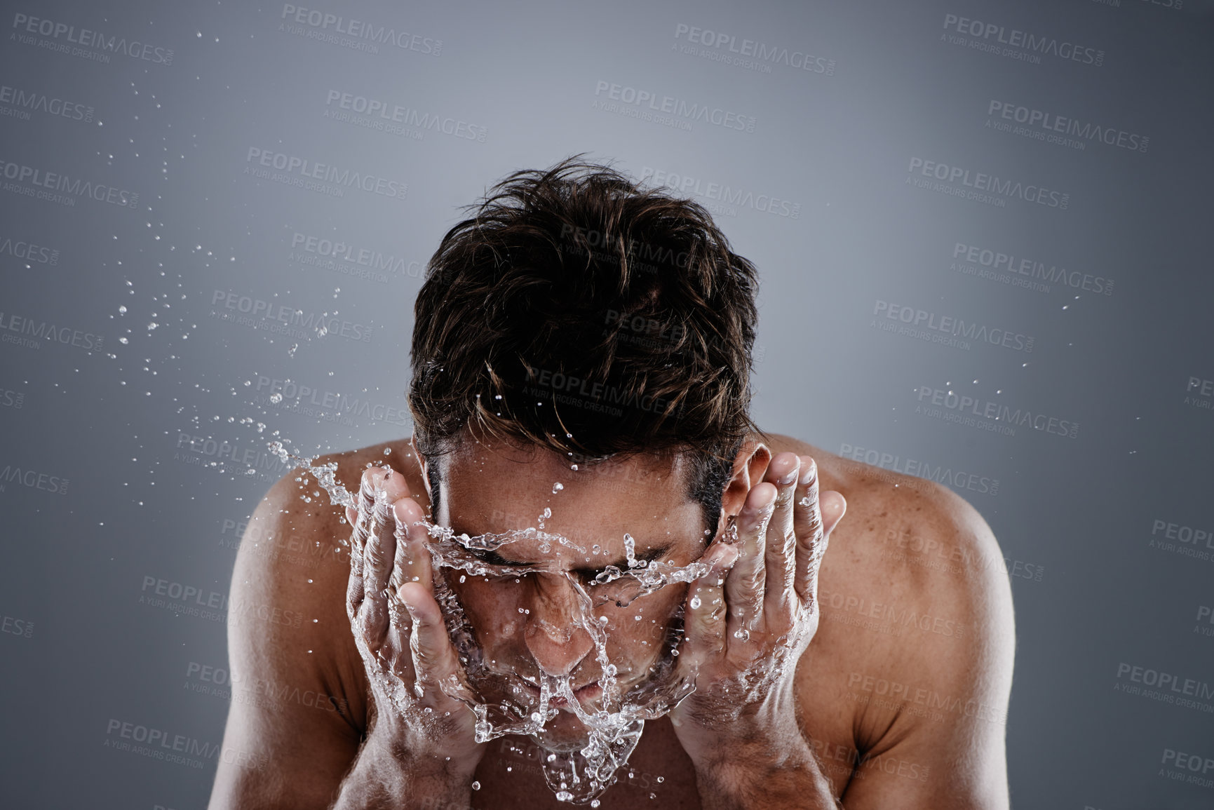 Buy stock photo Water splash, studio and man wash face for self care routine, morning facial cleanse or skincare. Liquid, wellness and person with hygiene treatment, grooming and skin cleaning on grey background