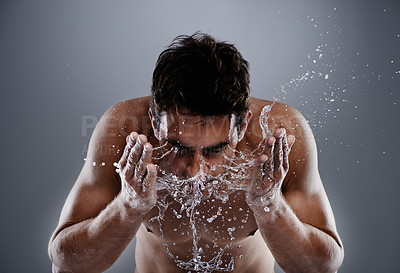 Buy stock photo Water drops, splash and man cleaning face for bathroom routine, dermatology cleanse or beauty treatment for skincare. Studio, moisture and model facial wash, hygiene and grooming on grey background