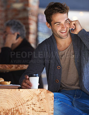 Buy stock photo Shot of a young man sitting in a cafe and talking on a cellphone