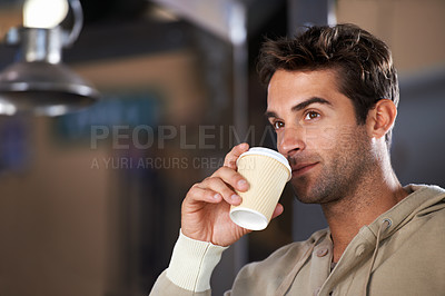 Buy stock photo Shot of a handsome young man drinking a coffee in a cafe