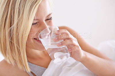 Buy stock photo A young woman drinking a glass of water before bed