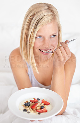Buy stock photo An attractive young woman eating her breakfast in bed
