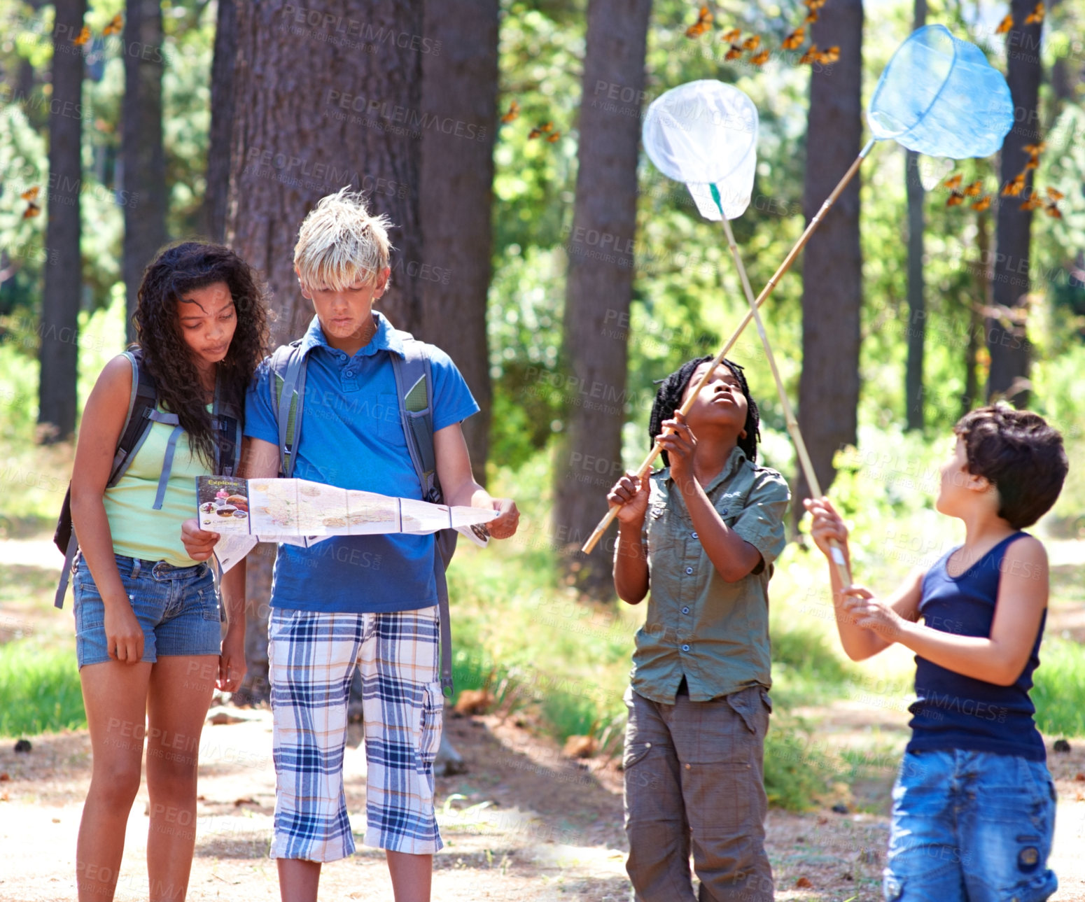 Buy stock photo Multi-ethnic kids exploring a map while standing outside in a forest