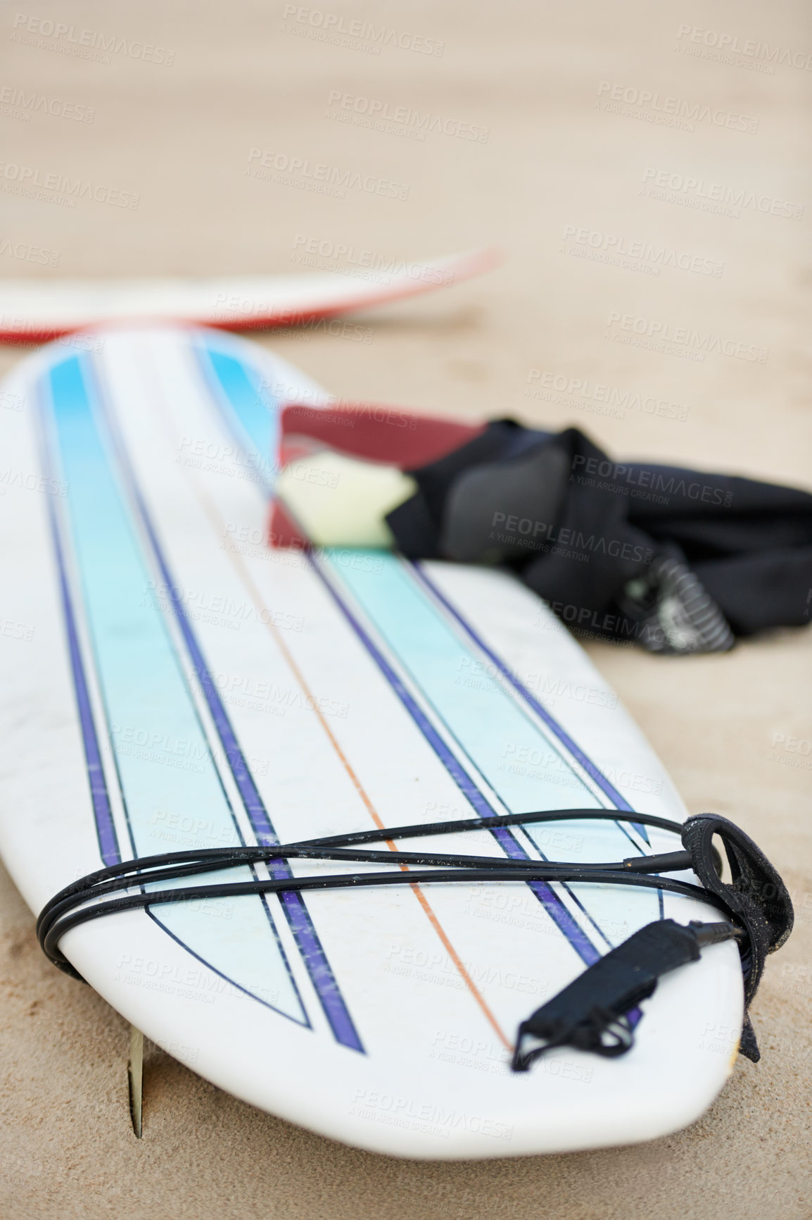 Buy stock photo A surfboard and wetsuit lying on the sand at the beach