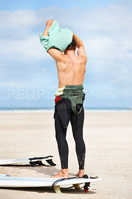 Buy stock photo Surfing, man and getting ready with surfboard on beach with wetsuit, blue sky and dressing with mock up space. Rear view, person and athlete by ocean for training, surfer workout and extreme sports 