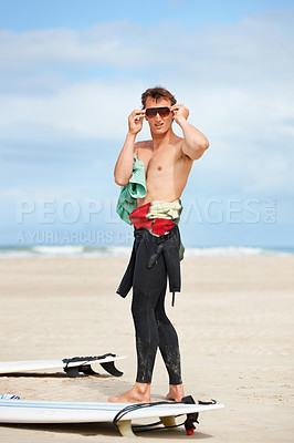 Buy stock photo Surfing, man and getting ready with sunglasses on beach with wetsuit, blue sky or surfboard with mock up space. Extreme sports, athlete and person by ocean for training, surfer workout or confidence 