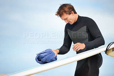 Buy stock photo Surfer, man and getting ready with surfboard on beach with wetsuit, blue sky and cleaning with mock up space. Extreme sports, athlete and person by ocean for training, surfing workout and towel 