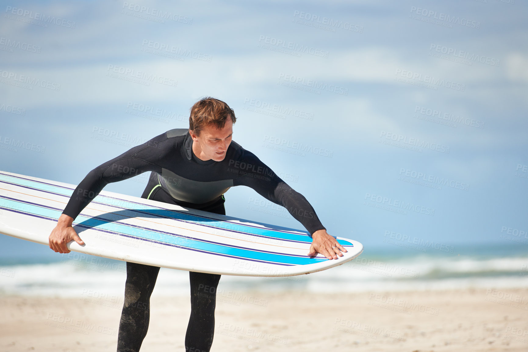 Buy stock photo Surfing, beach and man with surfboard by ocean for water sports training, exercise and fitness outdoors. Nature, travel and person check equipment for adventure on holiday, vacation and hobby by sea