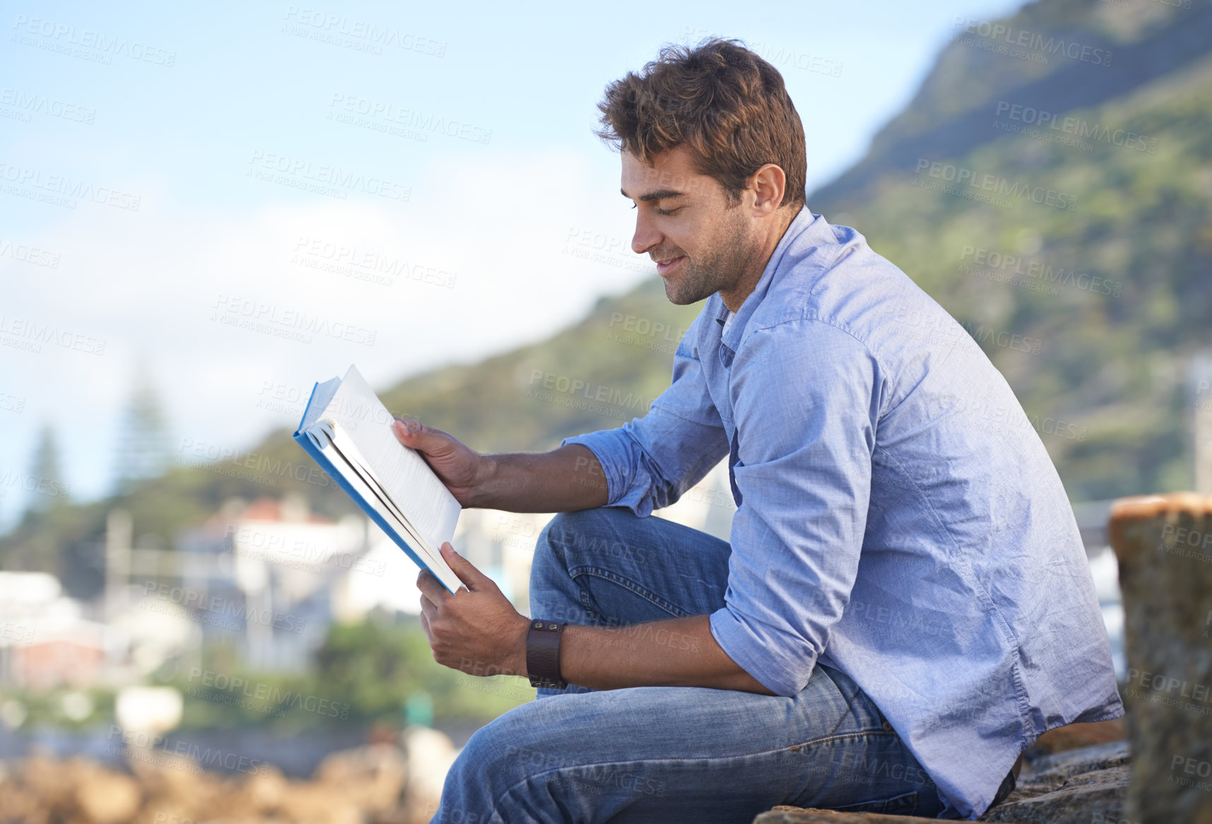 Buy stock photo A young man reading a book outdoors
