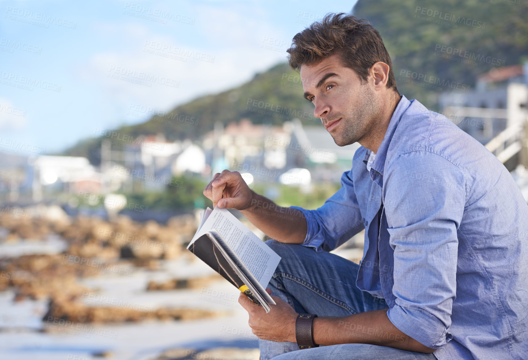 Buy stock photo Beach, book and young man reading for knowledge or relaxing hobby on vacation or holiday. Travel, outdoor and handsome confident male person enjoying story or novel on weekend trip or adventure.