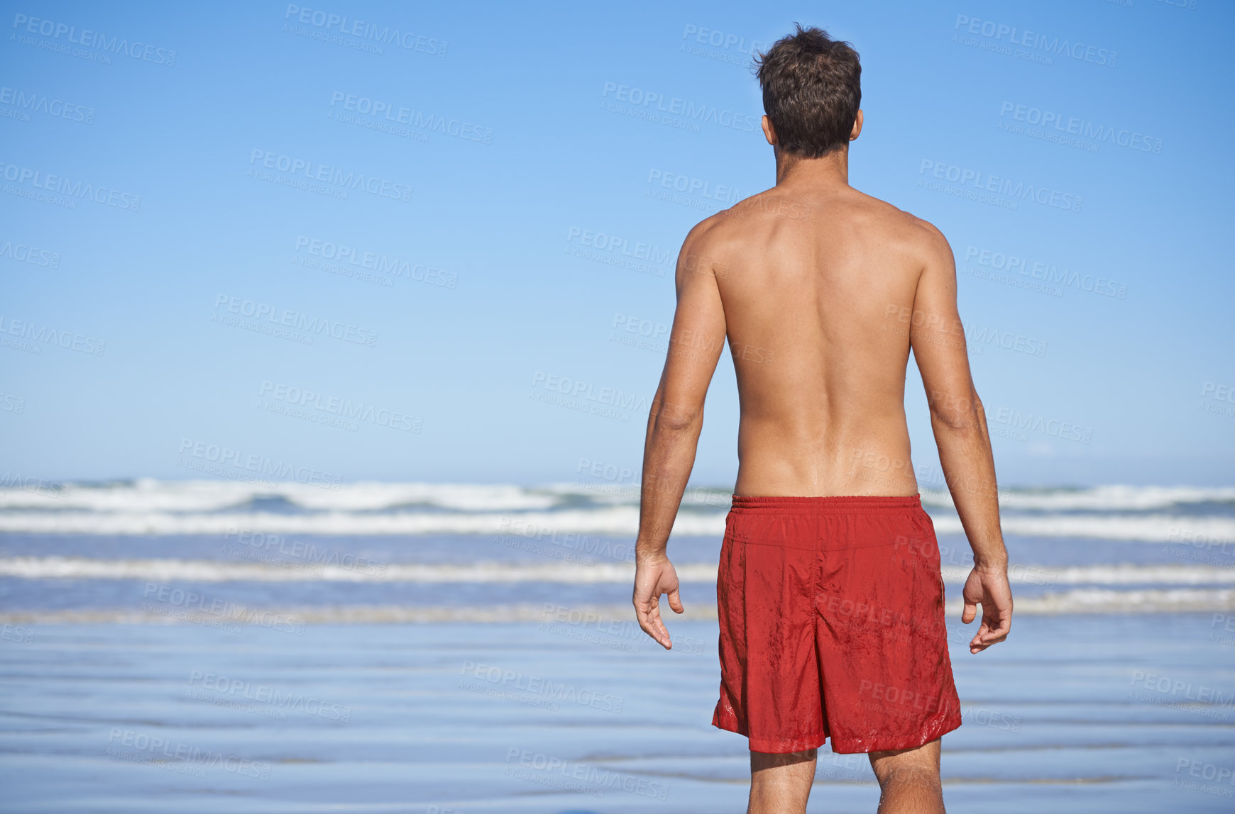 Buy stock photo Man, beach and waves for swimming, workout or outdoor exercise on the ocean coast in summer. Rear view or back of young male person or professional swimmer standing ready at sea on mockup space