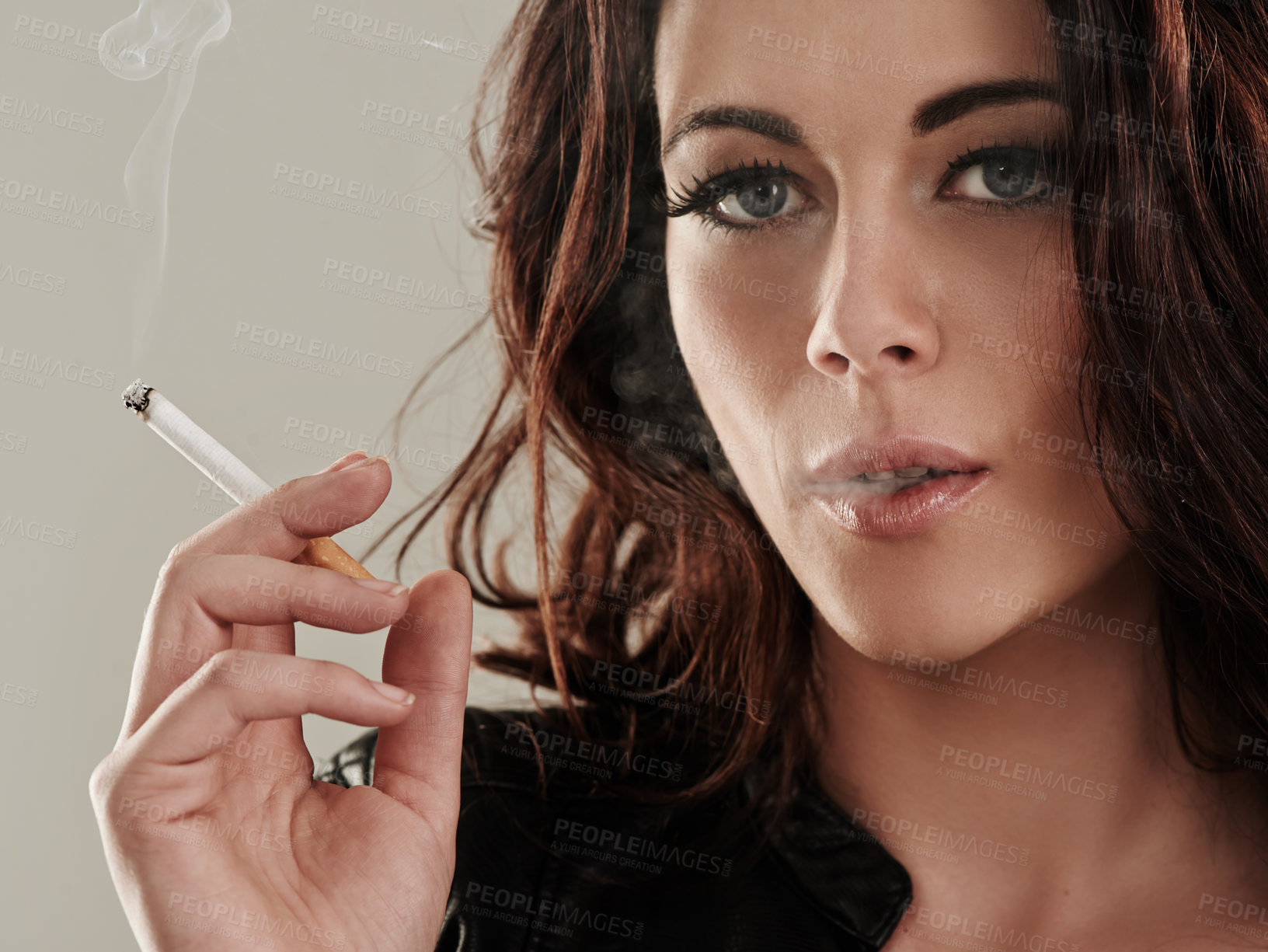 Buy stock photo Portrait of an attractive young woman smoking a cigarette 