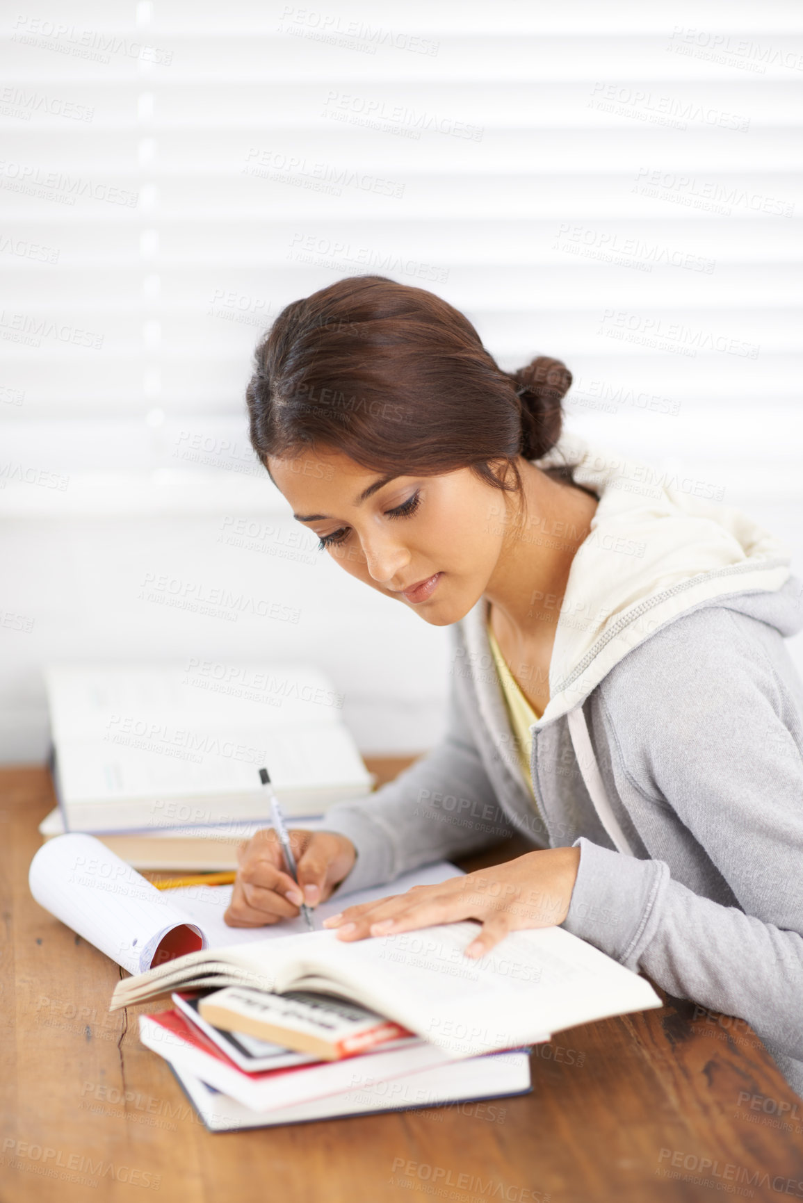 Buy stock photo Side view of a young college student taking notes from her textbook