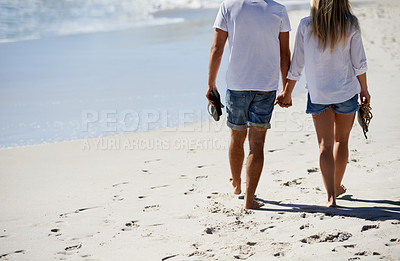 Buy stock photo Legs, holding hands and couple walking on beach for date, outdoor bonding and tropical holiday. Romance, man and woman from back, love and relax on vacation together with travel, care and adventure.